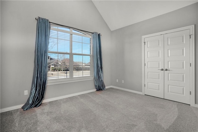 spare room with carpet flooring, baseboards, and lofted ceiling