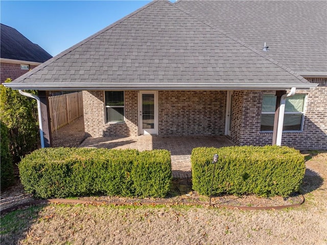 back of property with brick siding and roof with shingles