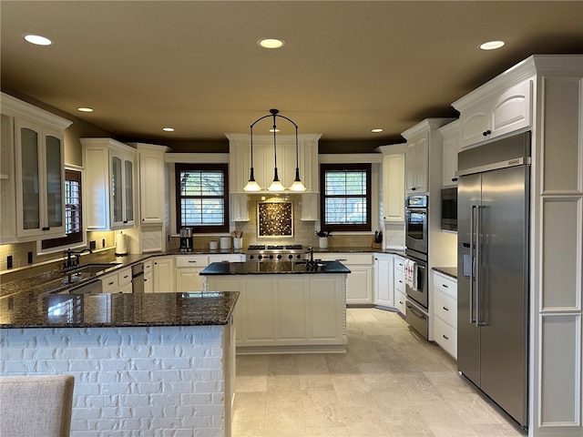 kitchen featuring built in appliances, a healthy amount of sunlight, a peninsula, and a sink