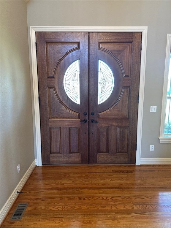 foyer featuring visible vents, french doors, baseboards, and wood finished floors