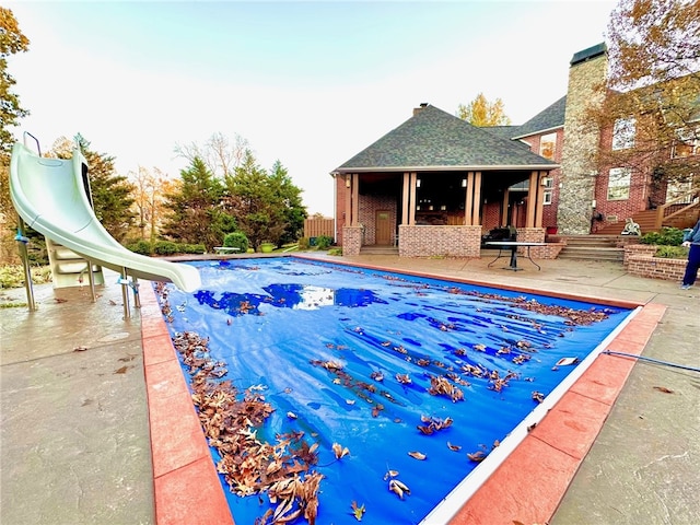 view of swimming pool with a fenced in pool, a patio, a water slide, and fence