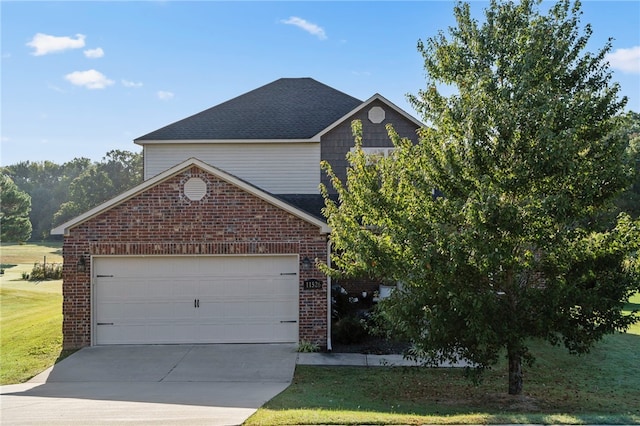 traditional-style home with driveway, roof with shingles, a front yard, an attached garage, and brick siding