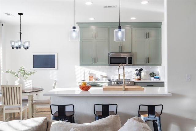 11526 Giles Rd, Farmington, AR 72730 - kitchen with stainless steel microwave, backsplash, a breakfast bar, a chandelier, and pendant lighting