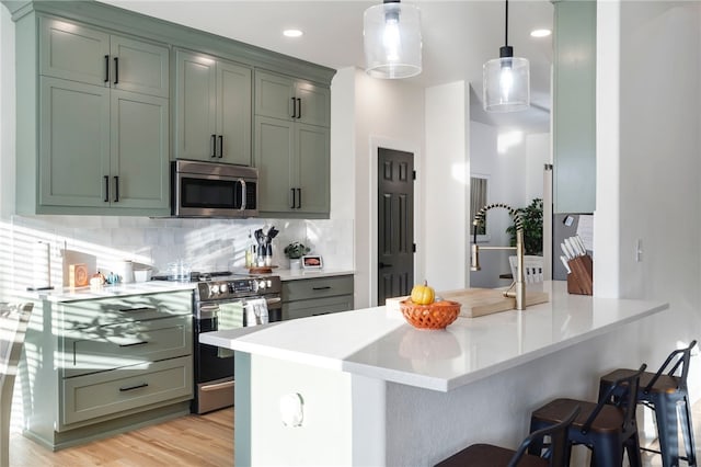 11526 Giles Rd, Farmington, AR 72730 - kitchen with stainless steel appliances, backsplash, a breakfast bar area, light countertops, and pendant lighting