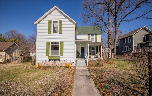 traditional home featuring covered porch, a front yard, and fence