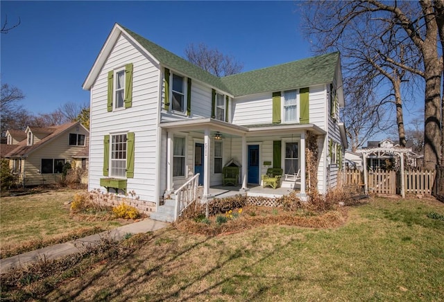 view of front of house featuring roof with shingles, covered porch, a front lawn, and a gate