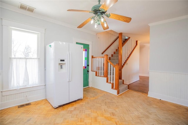 kitchen with a wealth of natural light, visible vents, white fridge with ice dispenser, and a wainscoted wall