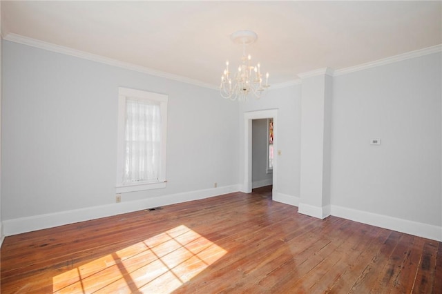 spare room with an inviting chandelier, hardwood / wood-style floors, and ornamental molding