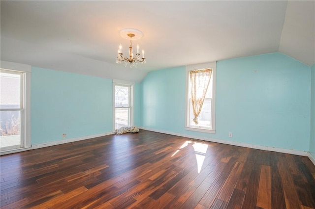 empty room featuring baseboards, lofted ceiling, an inviting chandelier, and dark wood-style flooring