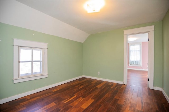 empty room with lofted ceiling, dark wood-style floors, and baseboards