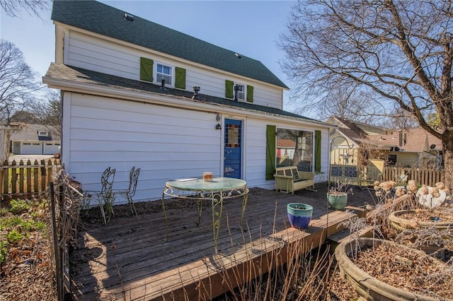 rear view of property with a wooden deck, a shingled roof, and fence