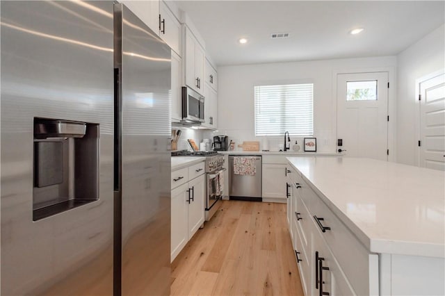 kitchen with visible vents, white cabinetry, light wood-style floors, appliances with stainless steel finishes, and light countertops