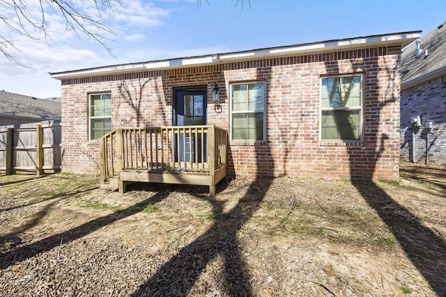 rear view of house featuring brick siding and fence