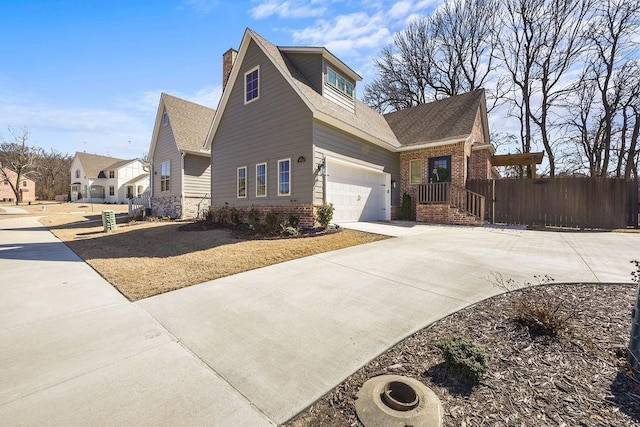 view of side of home with a garage, brick siding, driveway, and fence