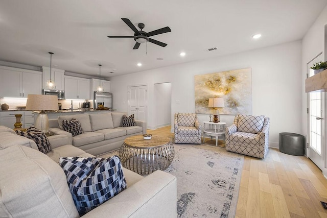 living room with visible vents, baseboards, ceiling fan, recessed lighting, and light wood-style flooring