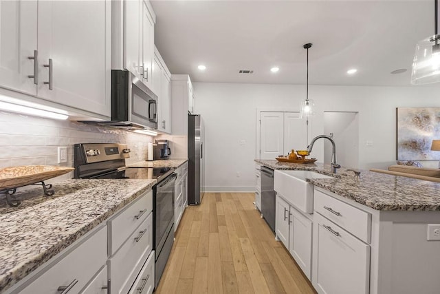 kitchen with visible vents, a sink, decorative backsplash, appliances with stainless steel finishes, and white cabinetry