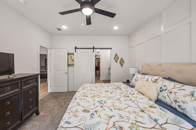 bedroom featuring visible vents, a ceiling fan, a barn door, a closet, and carpet flooring