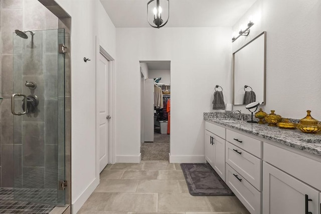 full bath featuring vanity, a spacious closet, baseboards, and a stall shower