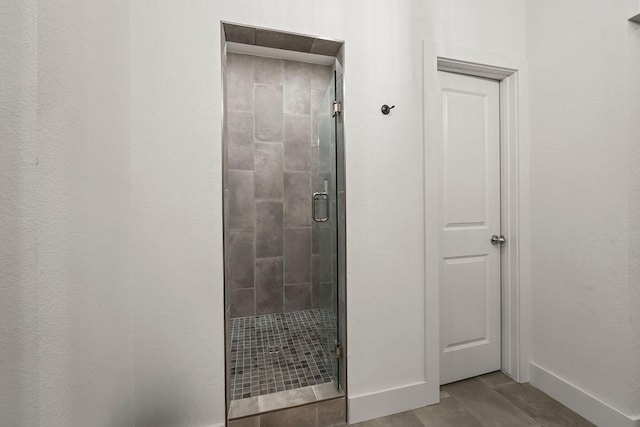 bathroom with a stall shower, baseboards, and wood finished floors