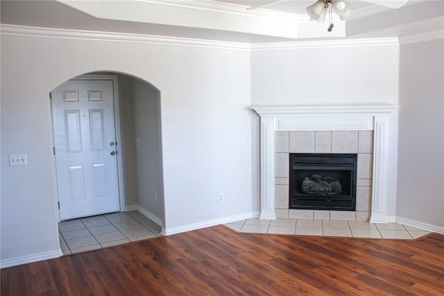 unfurnished living room with arched walkways, crown molding, a fireplace, and light wood-type flooring