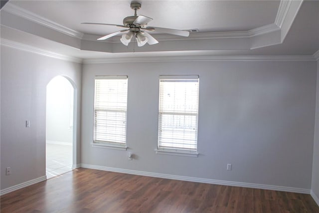 unfurnished room featuring a tray ceiling, a healthy amount of sunlight, and arched walkways