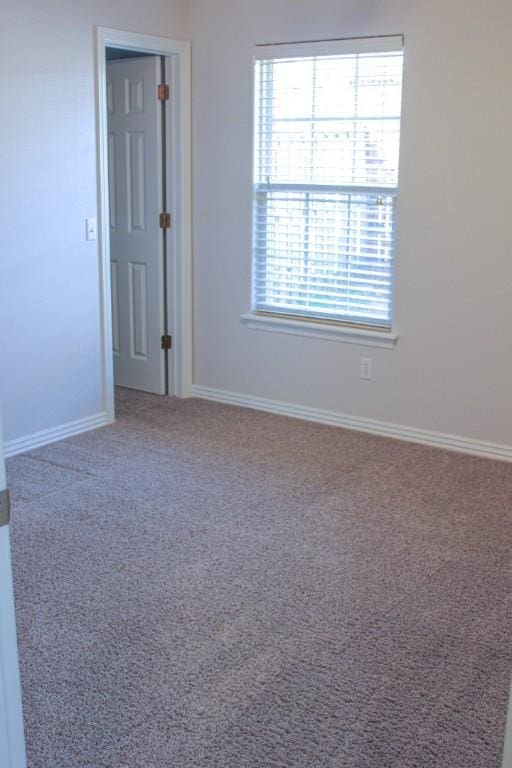 carpeted empty room with baseboards