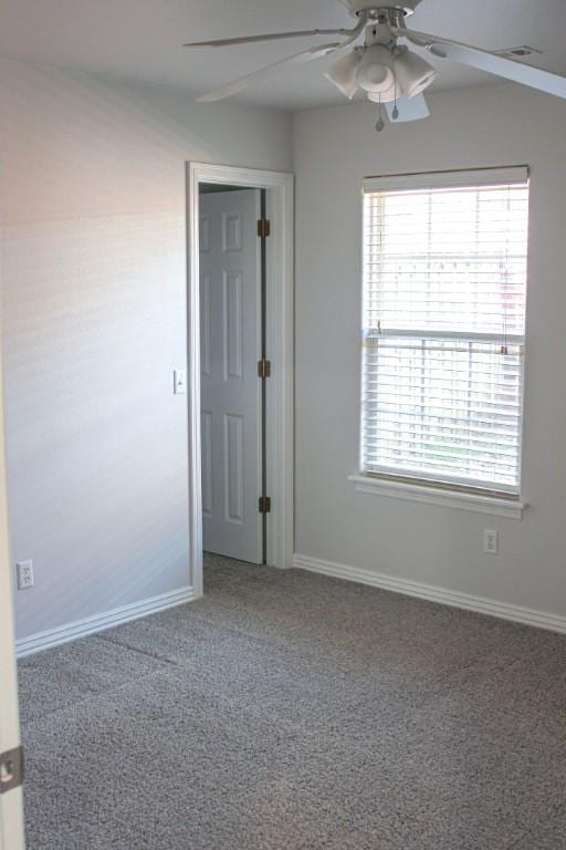 carpeted empty room featuring ceiling fan and baseboards