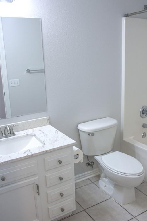 bathroom with tile patterned floors, toilet,  shower combination, and vanity