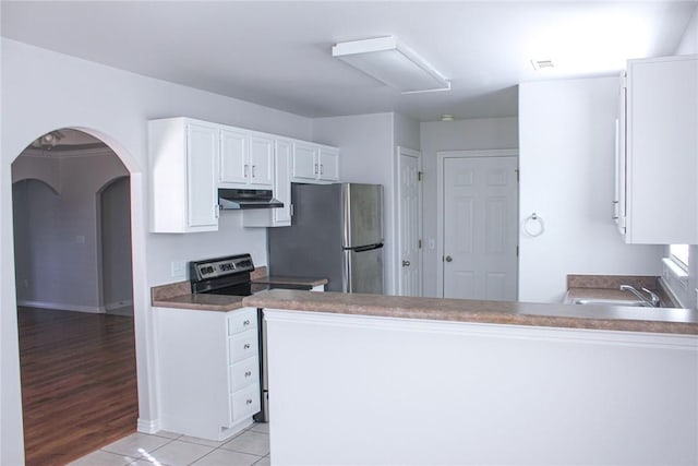 kitchen with under cabinet range hood, appliances with stainless steel finishes, light tile patterned flooring, arched walkways, and white cabinetry