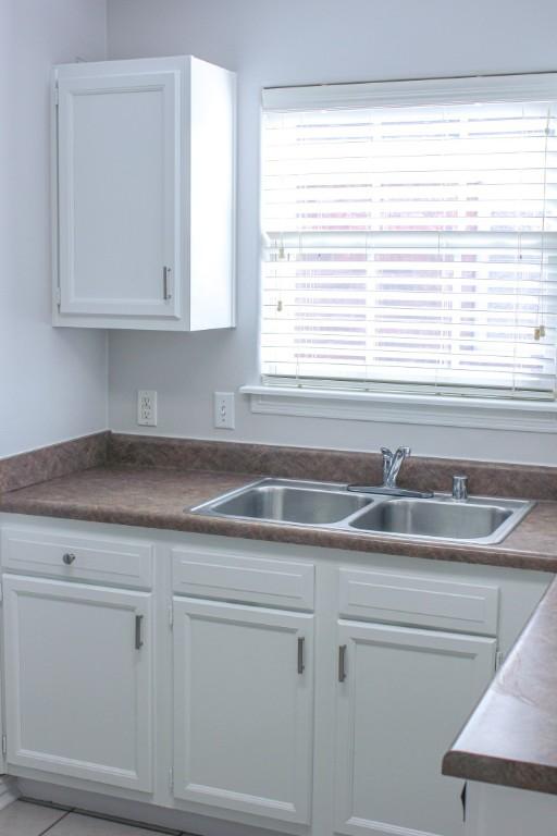 kitchen featuring white cabinetry, dark countertops, and a sink