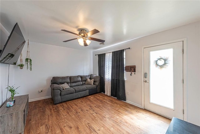 living area featuring ceiling fan, baseboards, plenty of natural light, and light wood-style flooring