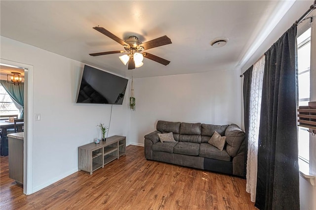 living room featuring ceiling fan, baseboards, and wood finished floors