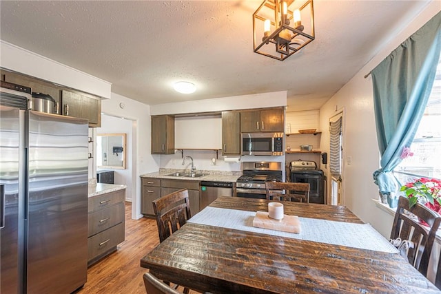 kitchen featuring a sink, a textured ceiling, wood finished floors, stainless steel appliances, and dark brown cabinets