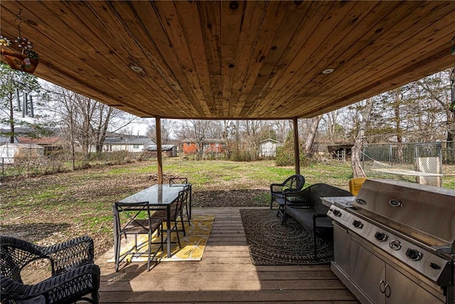 wooden deck featuring outdoor dining area, a yard, grilling area, and fence