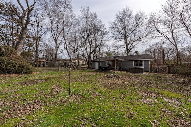 view of yard with a gate, fence, and a hot tub