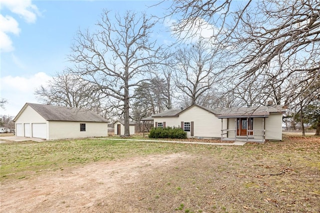 rear view of property featuring an outdoor structure, a lawn, and a garage