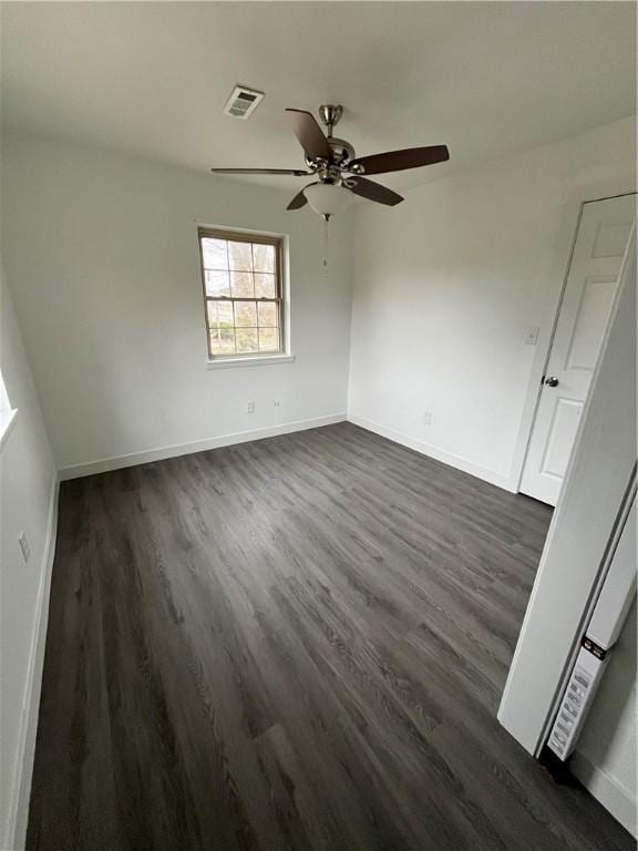 unfurnished room featuring dark wood finished floors, visible vents, a ceiling fan, and baseboards