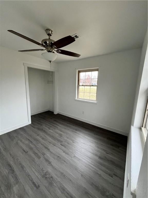 unfurnished bedroom with a closet, dark wood-type flooring, and baseboards