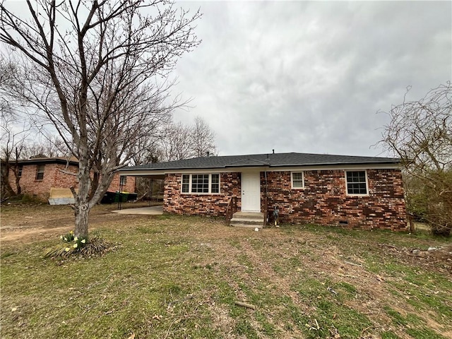 ranch-style house featuring brick siding, an attached carport, a front lawn, entry steps, and crawl space