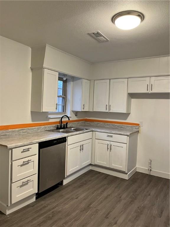 kitchen with dark wood finished floors, a sink, white cabinetry, and stainless steel dishwasher