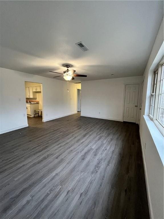 unfurnished living room with dark wood finished floors, visible vents, baseboards, and ceiling fan