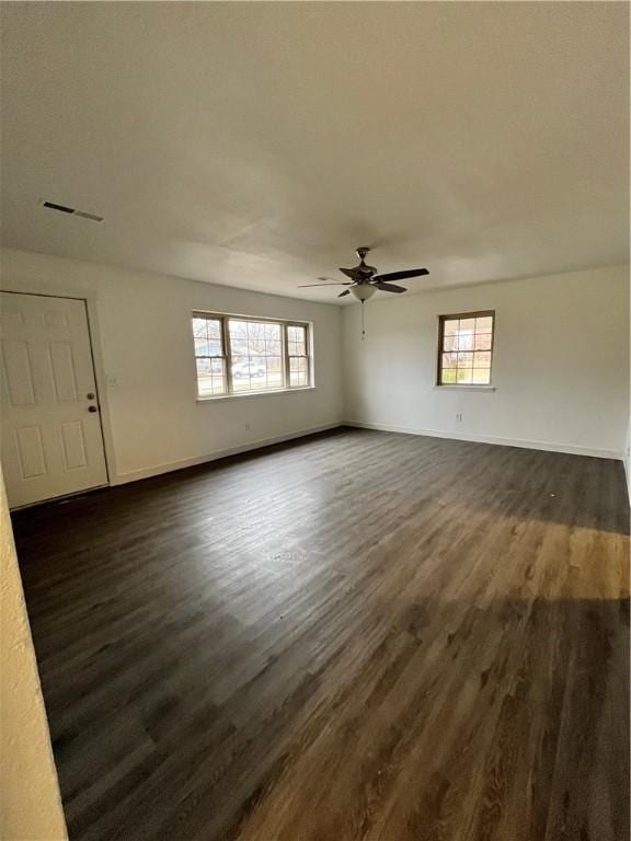 spare room featuring dark wood-style floors, visible vents, a healthy amount of sunlight, and baseboards