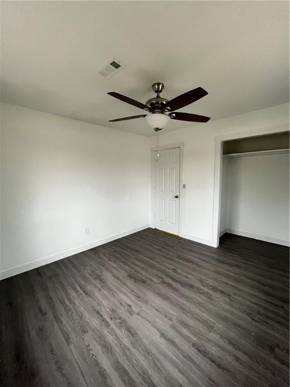 unfurnished bedroom with baseboards, visible vents, dark wood finished floors, ceiling fan, and a closet