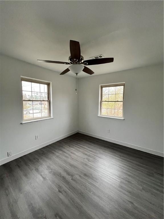 spare room featuring plenty of natural light, baseboards, and dark wood-style flooring