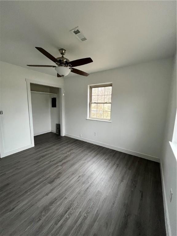 spare room with visible vents, baseboards, dark wood-style floors, and a ceiling fan