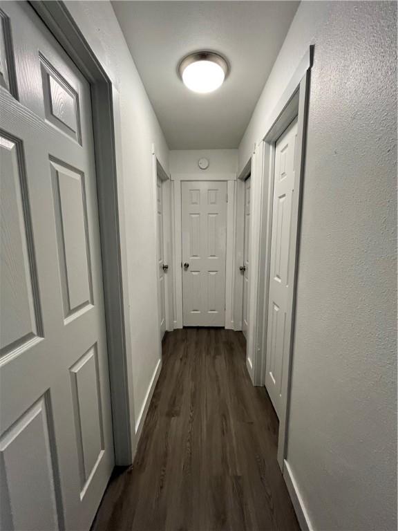 hallway with dark wood finished floors and baseboards