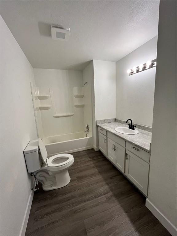 bathroom featuring vanity, washtub / shower combination, wood finished floors, baseboards, and toilet