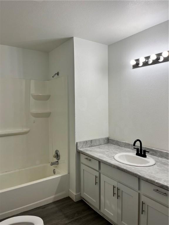 full bath with tub / shower combination, wood finished floors, and vanity