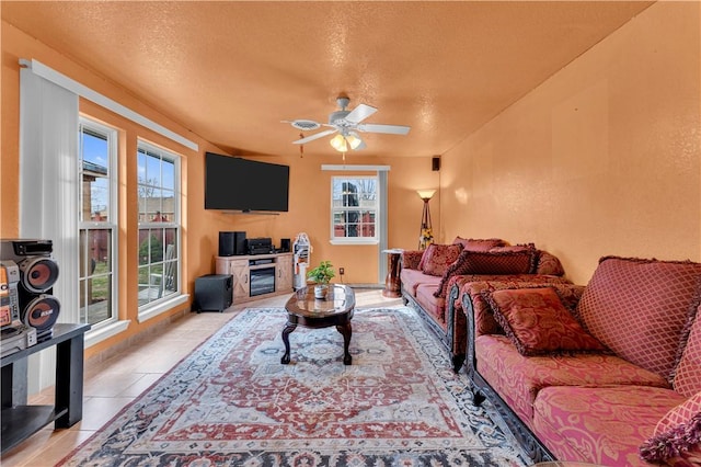 living area with light tile patterned floors, a textured ceiling, and a ceiling fan