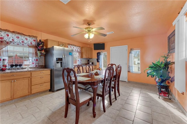 dining area featuring a healthy amount of sunlight, a textured ceiling, and a ceiling fan